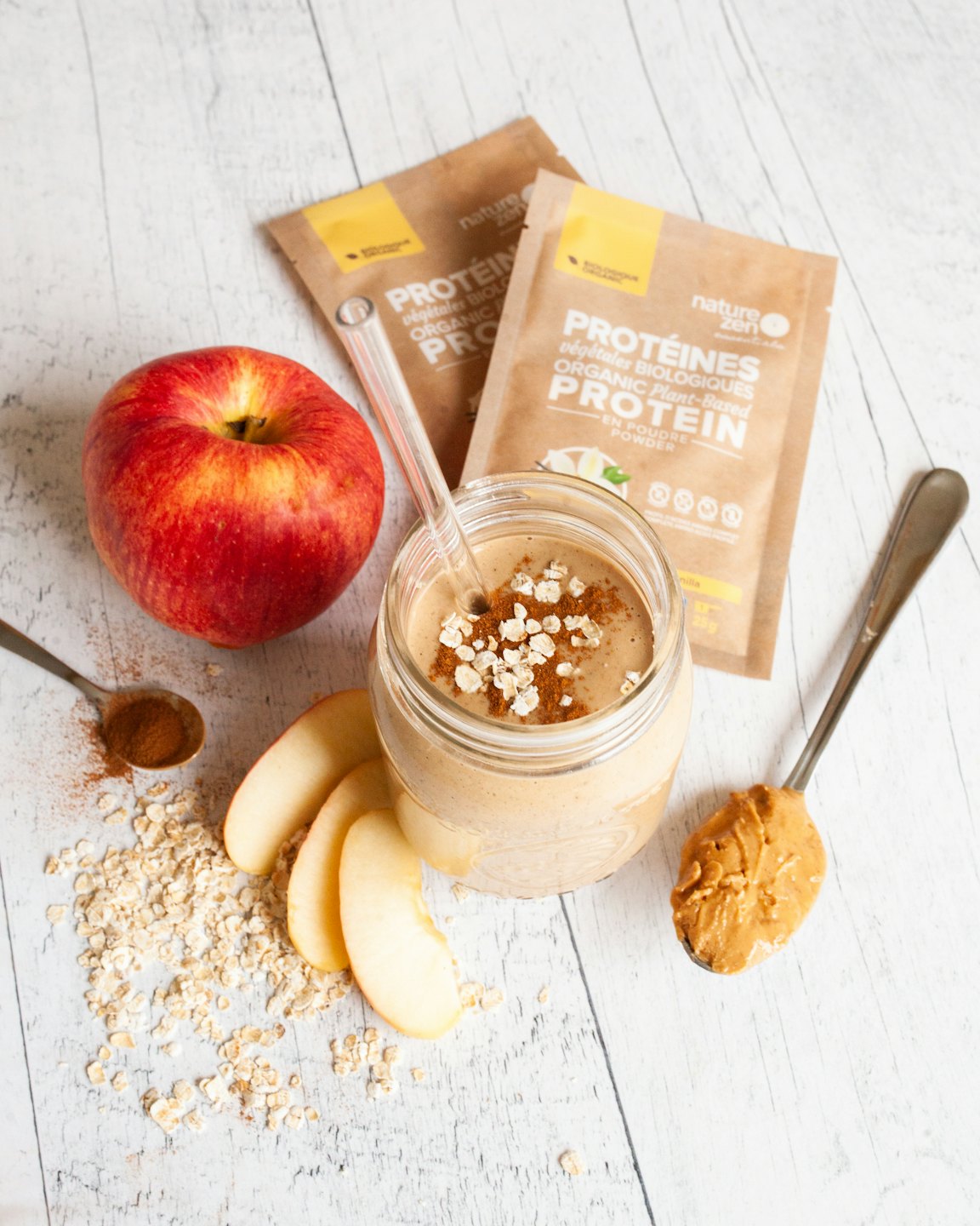 Glass smoothie jar surrounded by fruit, oats, and protein powder.